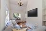Living area with wood finished floors, arched walkways, a desk, high vaulted ceiling, and a chandelier
