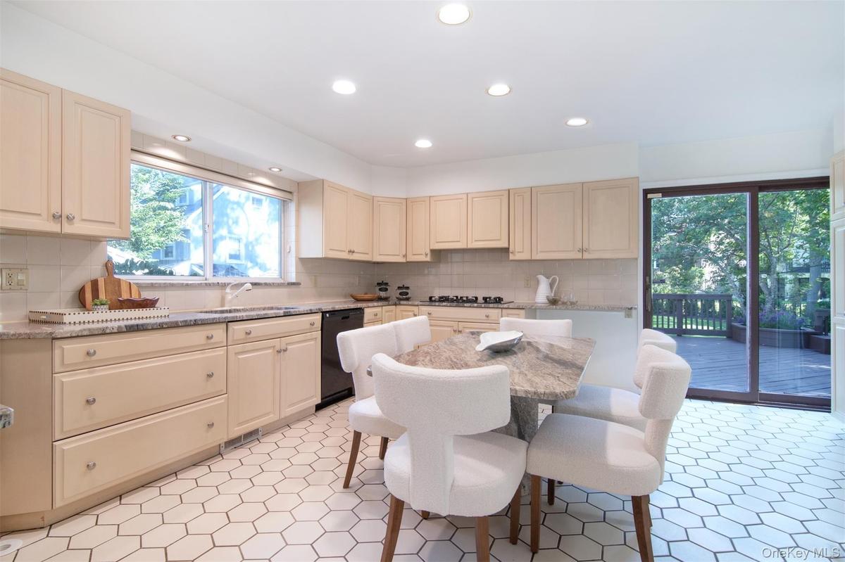 Kitchen featuring light stone countertops, cream cabinets, recessed lighting, and backsplash