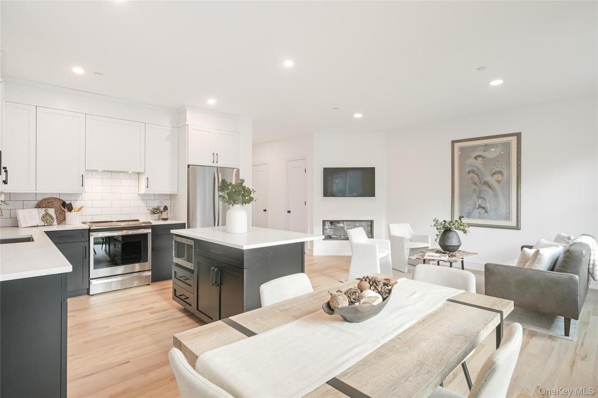 Kitchen featuring a kitchen island, tasteful backsplash, white cabinetry, stainless steel appliances, and light wood-type flooring