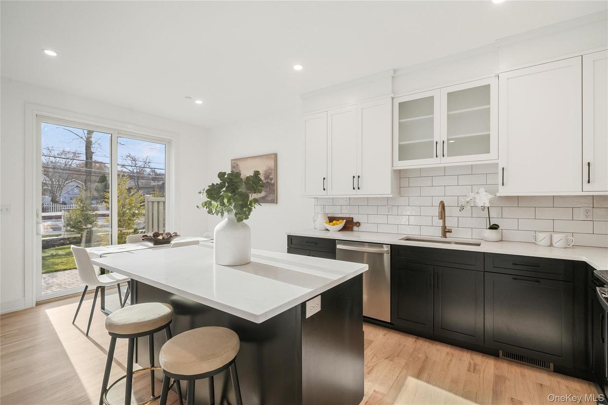 Kitchen featuring sink, a breakfast bar area, dishwasher, a kitchen island, and decorative backsplash
