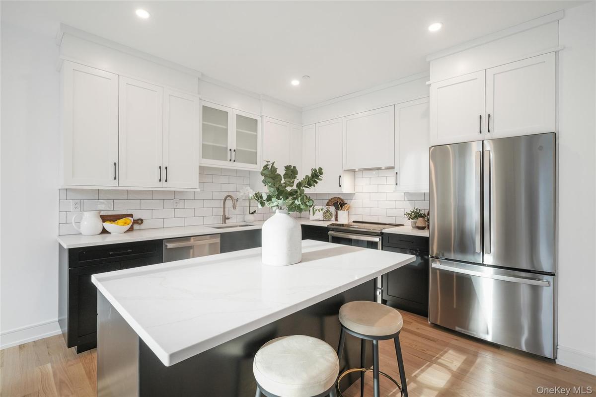 Kitchen featuring stainless steel appliances, a kitchen breakfast bar, white cabinets, and a kitchen island