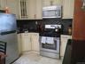 Kitchen featuring stainless steel appliances, black countertops, and a mosaic tile backsplash