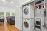 Dedicated laundry closet featuring a stacked washer and dryer, adjacent to an open-concept living space with multiple windows, recessed lighting, and 