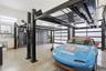 Spacious garage featuring a four-post car lift, polished concrete flooring, two overhead garage doors with frosted panels, and wall-mounted storage ca