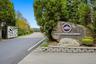 Entryway featuring a decorative metal gate, asphalt paving, and a stone monument sign