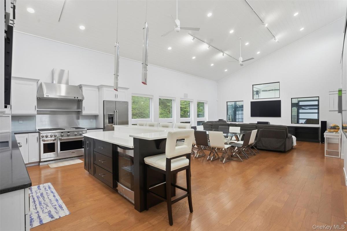 Open-concept living area featuring a vaulted ceiling with recessed lighting, wood-finish flooring, a gourmet kitchen with stainless steel appliances, 