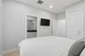 Recessed lighting illuminates the bedroom, featuring light-colored walls and carpet