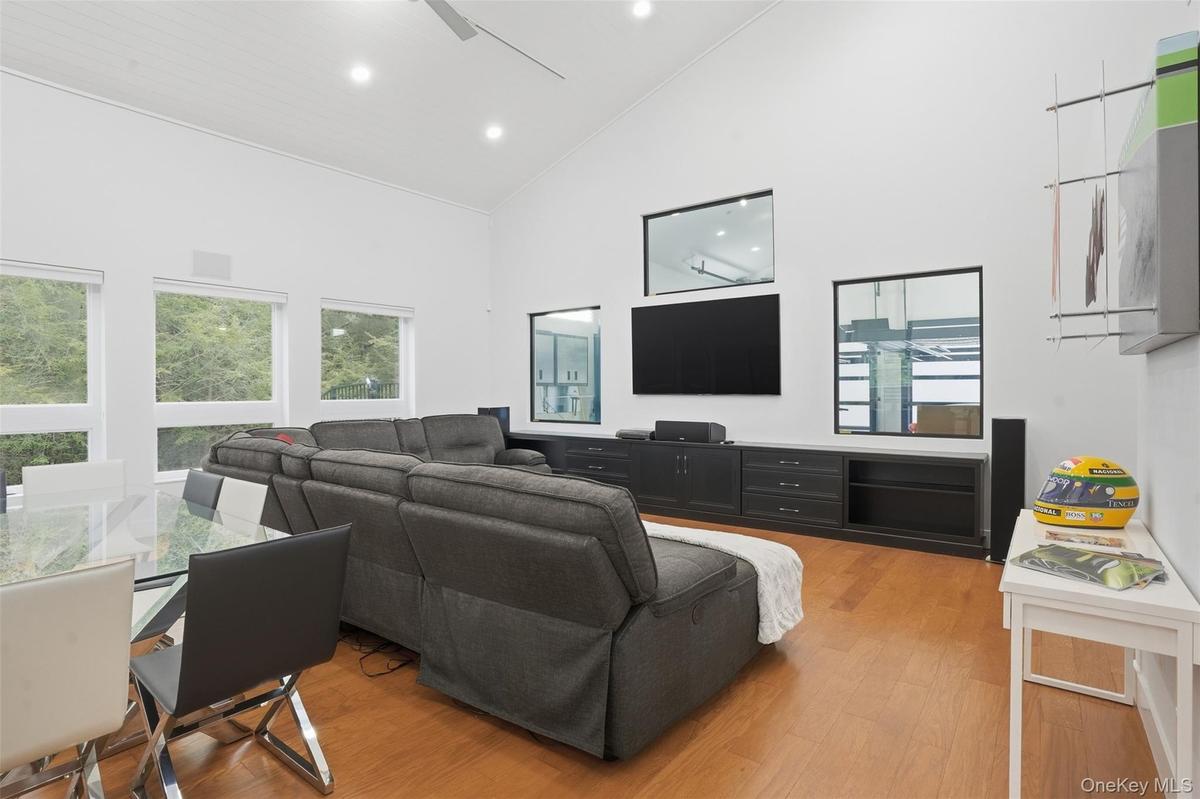 Open-concept living area featuring a vaulted ceiling with recessed lighting, wood-finish flooring, and multiple windows