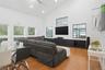 Open-concept living area featuring a vaulted ceiling with recessed lighting, wood-finish flooring, and multiple windows