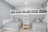 Built-in bunk beds featuring white wood construction and a white ladder