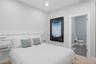 Bedroom with light gray walls, a white ceiling fan, and carpet flooring