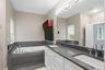 Dual vanity featuring white cabinetry, chrome fixtures, and a dark stone countertop