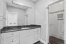 Bathroom featuring an expansive vanity with a dark countertop and undermount sink, white cabinetry with dark hardware, and a large wall-mounted mirror