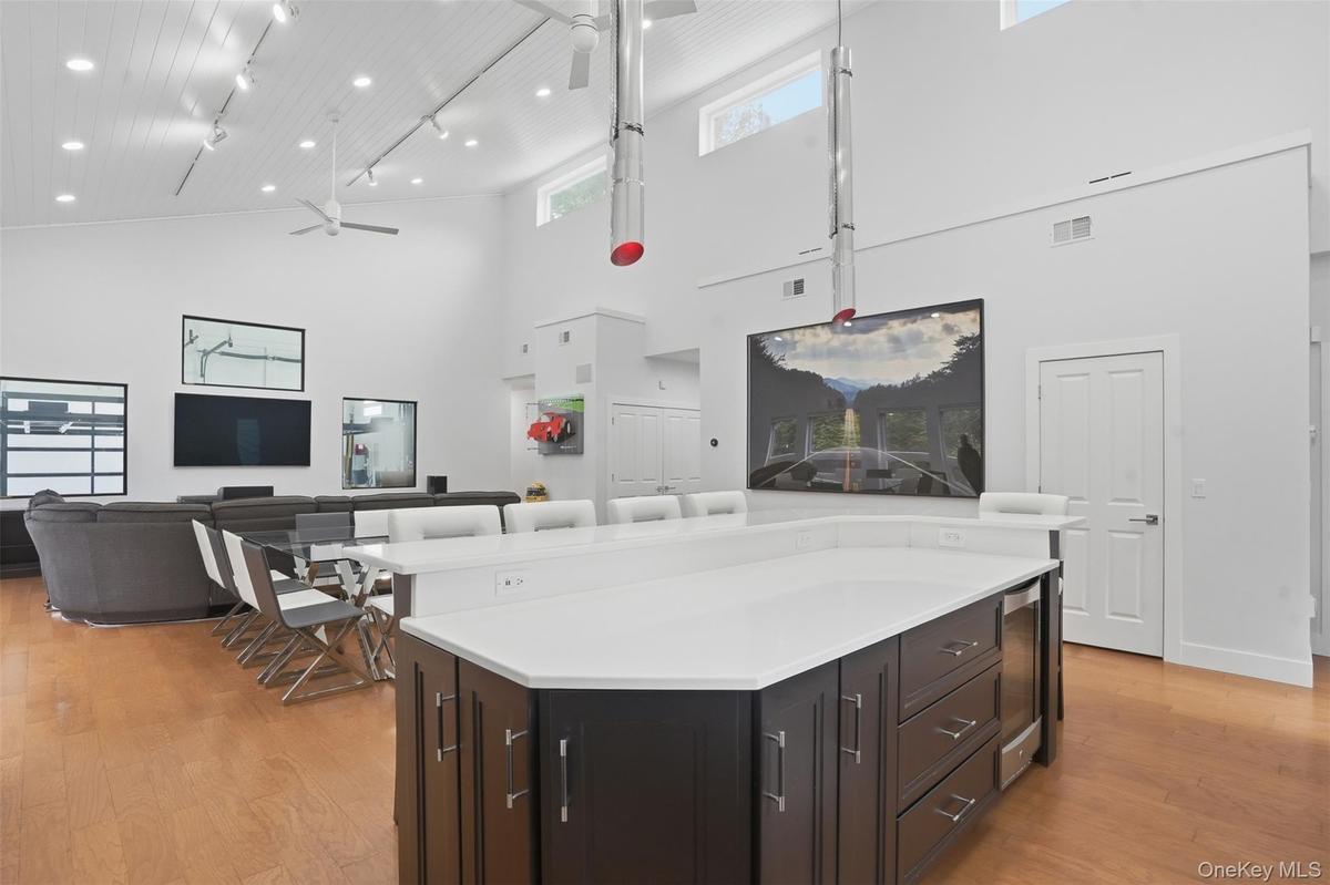 Spacious open-concept interior featuring a substantial kitchen island with white countertop, dark wood-finish cabinetry, and integrated beverage coole
