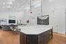 Spacious open-concept interior featuring a substantial kitchen island with white countertop, dark wood-finish cabinetry, and integrated beverage coole