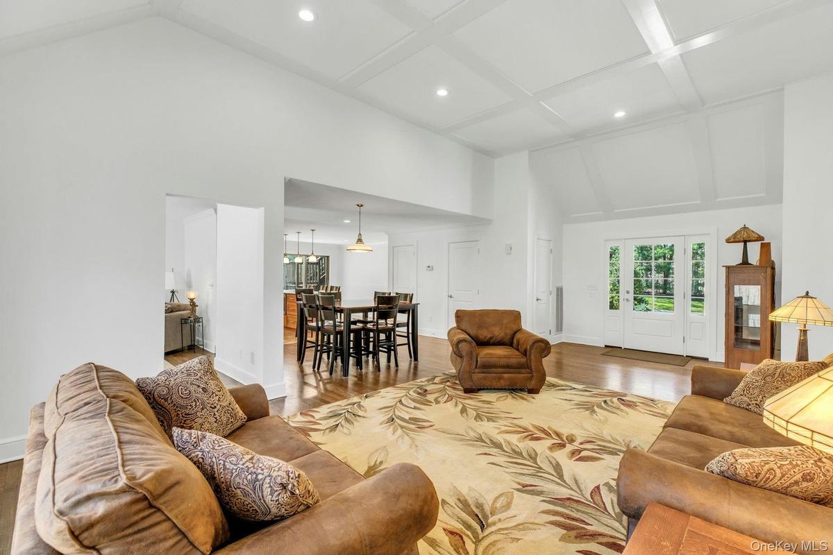 Spacious living area featuring wood-finish flooring, a coffered ceiling, recessed lighting, and a vaulted ceiling