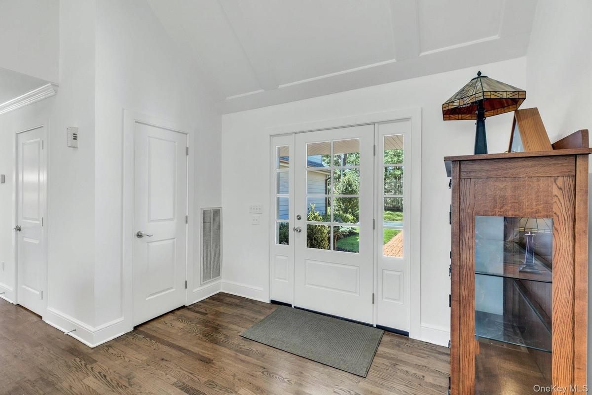 Entryway featuring a glass-paned door with side light, wood-finish flooring, white trim, and a high ceiling with a tray detail
