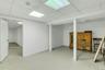 Spacious finished basement offering an open layout, drop ceiling with integrated lighting, white painted walls, and durable light-colored flooring