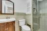 Bathroom featuring a glass-enclosed shower, a wall-mounted vanity with an integrated sink, a dark wood-finish framed mirror, and tiled walls with deco