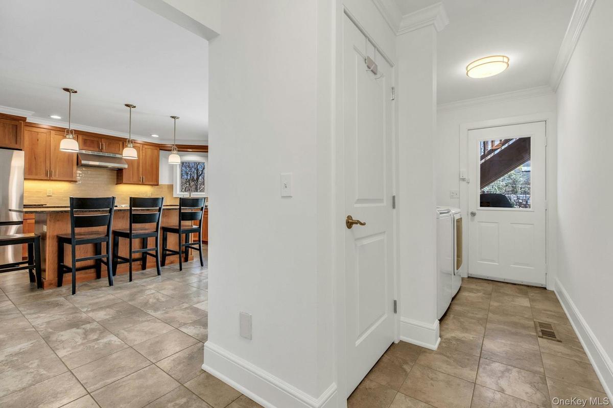 Bright hallway with tile flooring, crown molding, and a white paneled door