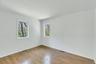 Room featuring wood-finish flooring, white baseboards, and two windows with white trim