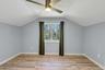 Room featuring sloped ceilings, light blue walls, and wood-finish flooring