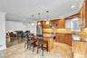 Spacious kitchen featuring warm wood cabinetry, granite countertops, stainless steel appliances, and tile flooring