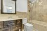 Bathroom featuring a dark wood-finish vanity with a light-toned countertop, an undermount sink, and a framed mirror