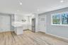 Apartment with Open-concept kitchen and living area featuring wood-finish flooring, recessed lighting, and a kitchen with white cabinetry