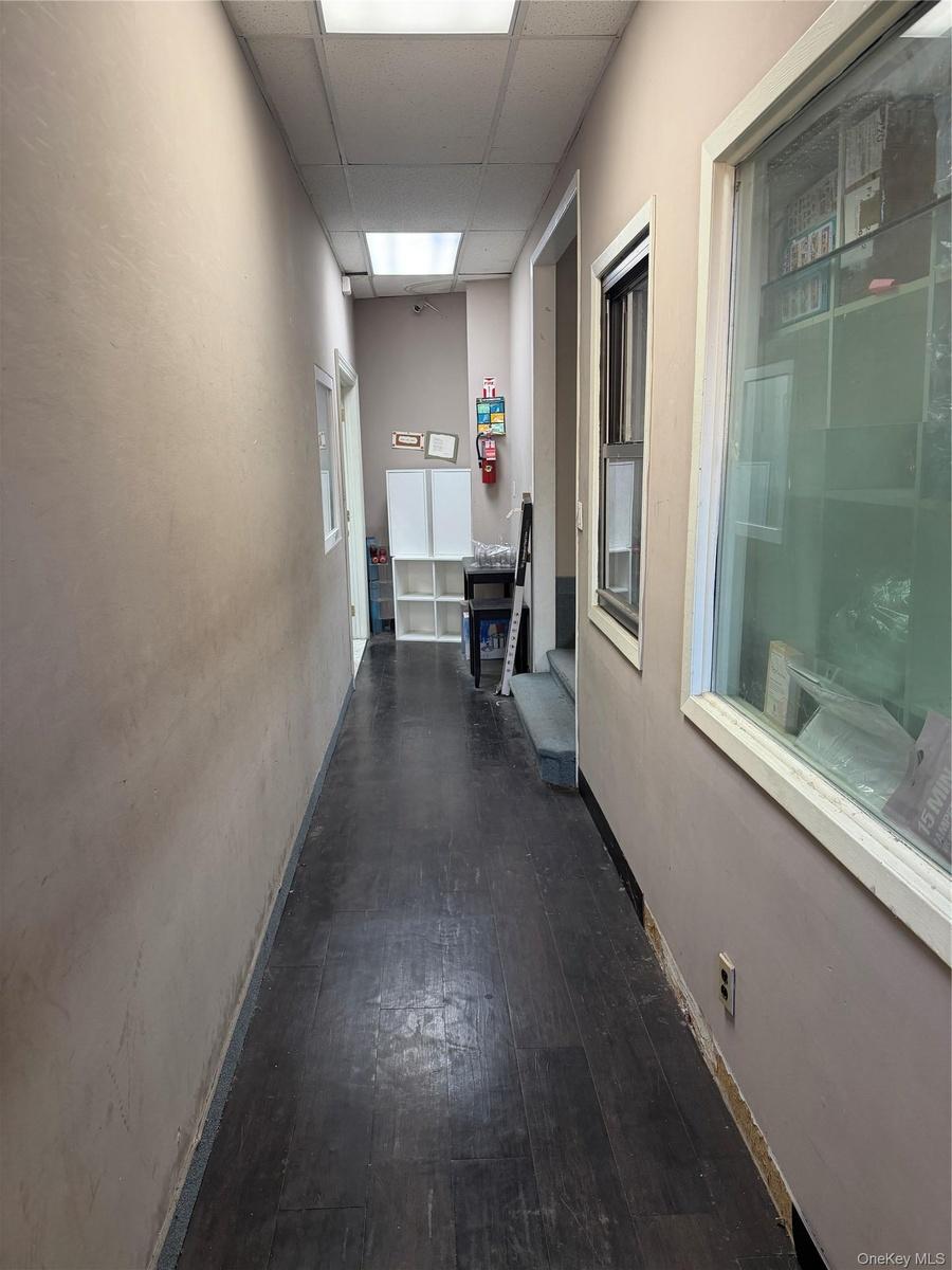 Hallway with a drop ceiling and dark wood-style floors