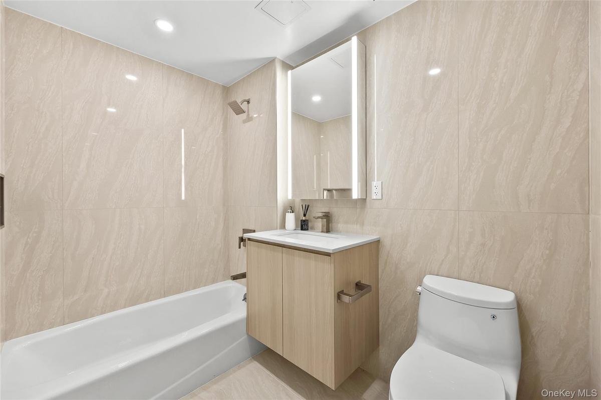 Full bath featuring vanity, shower / bath combination, tile walls, and recessed lighting