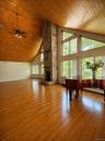 Spacious room featuring wood-finish flooring, a vaulted wood-paneled ceiling, a stone fireplace, large windows, and recessed lighting
