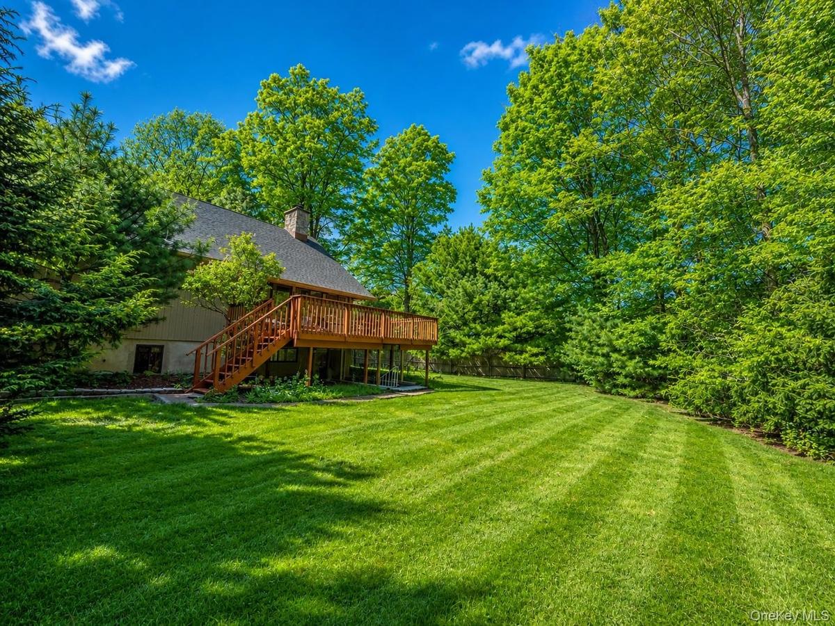 Expansive rear yard featuring a large wooden deck with staircase access