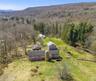 Outbuildings include: A two-story cow barn built in 1920 with 3,800 SF, a 480 SF barn dating to 1950, a detached one-car garage built in 1940 offering