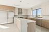 Kitchen with modern cabinets, appliances with stainless steel finishes, light stone counters, wall chimney range hood, and light tile patterned floori