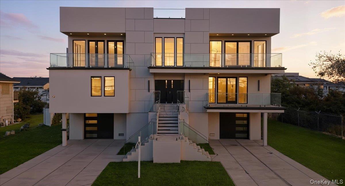 Contemporary house featuring a balcony, stairway, stucco siding, and concrete driveway