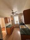 Kitchen featuring fridge, brown cabinets, dark wood-style floors, a ceiling fan, and a baseboard radiator