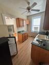 Kitchen with brown cabinets, dark countertops, a ceiling fan, light wood-style flooring, and fridge
