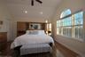 Bedroom featuring hardwood floors, high ceilings, large windows and recessed lighting.