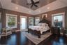 Main level Primary Bedroom suite with tray ceiling, hardwood floors, natural light, recessed lighting and direct access to rear deck.