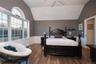 Bedroom featuring hardwood floors, high ceilings, large windows recessed lighting and ensuite bath access.