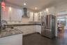 Kitchen featuring tile flooring, stainless appliance package, white cabinetry with ample storage and a stylish backsplash.
