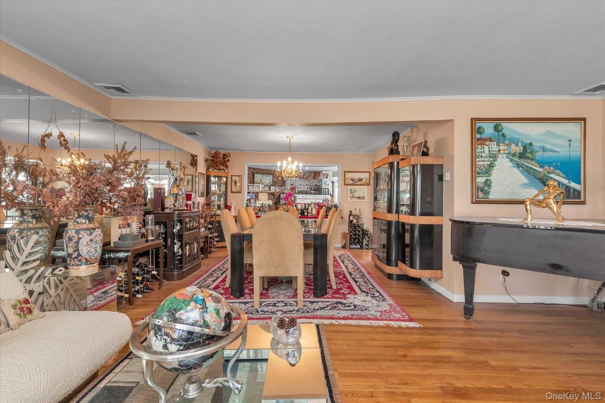 Hardwood flooring extends throughout this expansive interior space, featuring a dining area with a chandelier