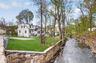 Flat backyard bordered by a peaceful channel of the Mamaroneck River, creating a unique natural setting.