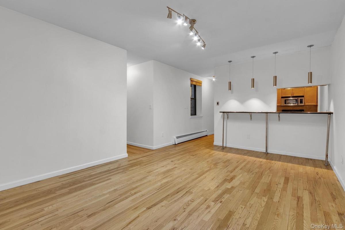Open-concept living area featuring wood-finish flooring, a breakfast bar with pendant lighting.