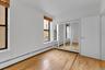Room with wood-finish flooring, two windows with blinds, and a mirrored closet