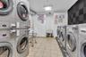 Dedicated laundry room featuring multiple front-loading washers and dryers
