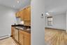 Compact kitchen featuring wood cabinetry, dark countertops, and stainless steel sink