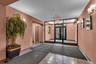 Building entrance featuring double glass doors with intricate wrought iron detailing, wall-mounted sconces, and a tiled floor