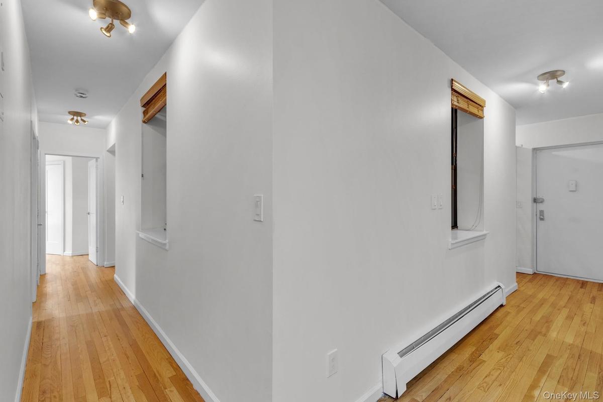 Hallway featuring wood-finish flooring and white painted walls